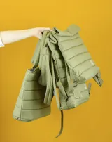 Mochila de diseño acolchado con acabado impermeable, color verde oliva. Presenta correas ajustables, compartimento principal con solapa y detalles de costuras horizontales.