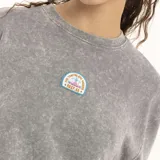 Remera gris con efecto lavado, cuello redondo y logo estampado en el frente.