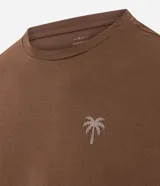 Remera marrón de algodón, corte comfort, con cuello redondo y mangas cortas. Presenta un pequeño estampado de palmera en el pecho.