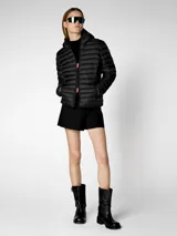 Campera puffer beige con capucha, cierre frontal con cremallera naranja, bolsillos laterales ocultos y logo de goma en la manga. Confeccionada en nylon liviano y con puños y dobladillo elásticos de Lycra.