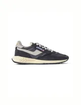 Championes Autry modelo Reelwind Low, inspirados en el estilo runner de los años 80. Presentan un diseño en color negro con detalles en gris claro, confeccionados en una combinación de ante y malla transpirable. Incluyen el logo de la marca en el lateral y en la lengüeta, con una suela de goma amortiguada de aspecto vintage.