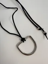Collar con dije de estribo metálico plateado y cordón de cuero sintético color bordó con terminales plateadas.