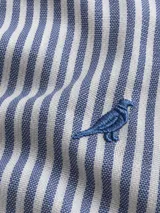 Camisa de lino de corte slim fit, con diseño de rayas verticales celestes y blancas, manga larga y cuello camisero. Cuenta con cierre frontal de botones y detalle de bordado de ave en el pecho.