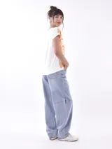 Remera de manga corta, cuello redondo, color blanco con estampado en azul que simula una escena tropical vista desde un interior, con plantas y una figura sentada.