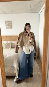 Chaleco de punto color beige con escote en V, diseño de trenzas verticales y tres flores tejidas en relieve.