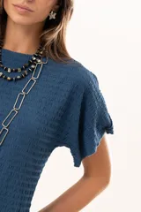 Blusa de silueta relajada y cuello redondo, confeccionada en tela liviana con textura. Presenta mangas cortas y una caída suelta.