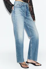 Jeans wide leg de tiro alto y cinco bolsillos, confeccionados en denim con lavado azul medio y efecto desgastado. Presenta cierre frontal con cremallera y botón metálico.