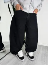Pantalón de corte baggy confeccionado en pana negra, con diseño de tiro medio y pernera ancha.
