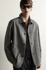Sobrecamisa gris de corte regular fit con textura, cuello solapa, cierre frontal de botones, bolsillos de parche en el pecho y los laterales, y mangas largas con puños abotonados.