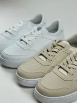 Zapatillas deportivas de cuero sintético, con cordones y suela blanca.