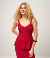 Blusa femenina color rojo, confeccionada en algodón y poliéster con efecto punto. Diseño sin mangas, con breteles anchos, escote en V, modelo ajustado en el busto con recorte horizontal y acabado peplum en el ruedo.