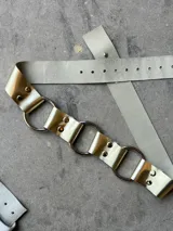 Cinturón marrón con textura símil piel de cocodrilo, argollas plateadas y remaches.