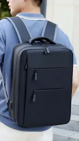 Mochila urbana de diseño minimalista y estructura rígida, color negro. Cuenta con múltiples compartimentos frontales con cierre, puerto USB integrado y correas acolchadas para los hombros.