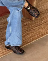 Suecos con estampado animal print en tonos marrones y negros, con detalle de triángulo dorado en el empeine.