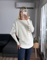 Sweater color marrón de manga murciélago oversize, con escote barco y bordado de lentejuelas y canutillos al tono en hombros y mangas.