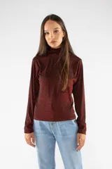 Remera de manga larga con cuello polera, confeccionada en tejido brillante con acabado metalizado en color bordó. Presenta un ajuste regular.