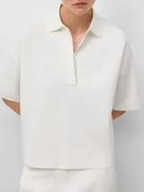Polo de punto color blanco, con cuello polo, escote en V y mangas cortas de corte holgado.