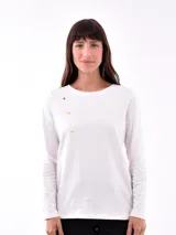 Remera blanca de manga larga con cuello redondo y detalle de tres botones dorados en el hombro izquierdo.