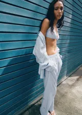 Pantalón largo de popelín celeste con estampado de rayas verticales, cintura elástica ajustable y detalles de lentejuelas brillantes.
