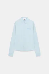 Camisa de denim en tono celeste claro, de manga larga con puños abotonados, cuello camisero clásico y cierre frontal de botones. Cuenta con el logotipo de Fruit of the Loom bordado a tono en el pecho.