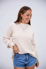 Sweater de tejido de punto acanalado en color crudo, con cuello redondo y mangas largas con puños ajustados.