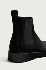Bota chelsea de cuero con acabado de serraje color negro, con elásticos laterales y tira trasera para facilitar el calce.