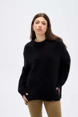 Sweater de punto negro, con cuello redondo a la base, manga larga y diseño holgado.