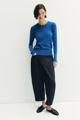 Jersey Zara de punto liso color negro, con cuello redondo, manga larga y detalle de botones dorados en los puños.