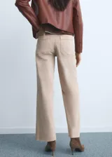 Jeans tiro alto estilo culotte de color beige claro, con diseño de pernera ancha, bajo deshilachado y cierre de cremallera y botón.