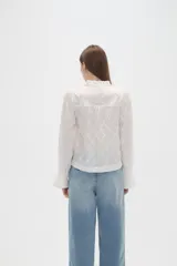 Blusa de viscosa color bordó con diseño bordado geométrico, cuello en V y mangas largas con terminación en volados.