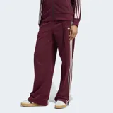 Pantalón deportivo Adidas Firebird de corte holgado, color bordó con las icónicas tres rayas laterales en blanco y logo del trébol bordado. Presenta cintura de tiro medio y diseño de pierna ancha.