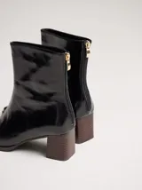 Botas de caña media color marrón, confeccionadas en cuero con acabado brillante. Presentan punta cuadrada, taco de madera y un distintivo bordado decorativo en color rojo que recorre el empeine hasta la punta.
