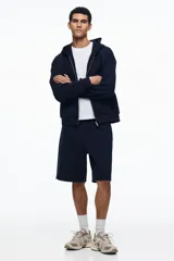 Short de felpa interlock color negro, de corte relajado a la rodilla, con cintura elástica con cordón ajustable oculto y bolsillos laterales.