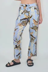 Pantalón celeste de corte recto y tiro alto, confeccionado en mezcla de lino y algodón, con estampado selvático que incluye tigres y hojas en tonos marrones y beige.