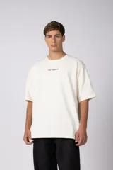 Remera oversize de algodón color beige, de manga corta y cuello redondo, con pequeño estampado frontal de la marca en tono bordó.