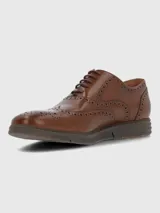 Zapato tipo oxford de cuero color marrón con diseño brogue, cordones al tono y suela de goma tipo deportiva.