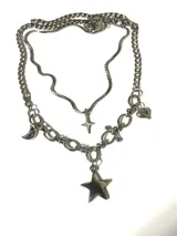 Collar doble de acero quirúrgico compuesto por una cadena fina con dije de estrella de cuatro puntas y una cadena de eslabones más gruesos con dijes colgantes de luna, estrella grande y corazón.