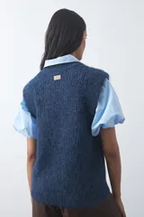 Chaleco de punto con textura afelpada, cuello redondo y hombros marcados. Presenta una silueta relajada y un diseño sin mangas.