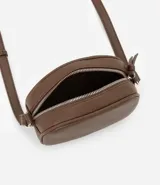 Cartera tipo camera bag pequeña, color marrón camel, de forma ovalada con superficie texturizada. Cuenta con correa ajustable larga, cierre principal con cremallera dorada y un pequeño bolsillo frontal con cremallera.