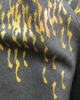 Túnica beige de gabardina de lana estampada con diseño abstracto en tonos ocre. Cuenta con cuello mao, bolsillos laterales y dos piezas a modo de bufandas que se pueden anudar de diferentes maneras.