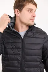 Campera capitoneada color azul marino, con capucha de algodón gris desmontable y cierre frontal. Tiene dos bolsillos exteriores con cierre.