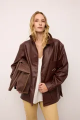 Chaquetón de cuero oversized color marrón, con corte recto, cuello camisero y cierre frontal de botones. Presenta bolsillos delanteros con bordados inspirados en la costa atlántica.