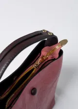 Cartera tipo bucket color rosa con detalles en marrón. Tiene correa de hombro ajustable con rayas horizontales blancas y rosas.