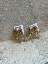 Aros colgantes hechos a mano con bronce, porcelana, piedras y otros materiales que le dan textura. Cada par es único e irregular.