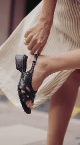 Sandalia de cuero color negro, con taco cuadrado de 4 cm, tiras entrelazadas en el empeine y tira ajustable con hebilla en el talón.