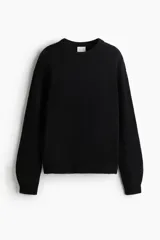 Buzo negro de tejido suave con lana, cuello redondo acanalado, hombros caídos y mangas largas. Puños y bajo en punto acanalado.