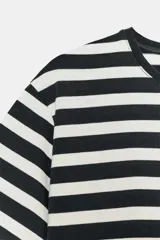 Camiseta de algodón con diseño de rayas horizontales en blanco y negro, cuello redondo y manga corta. Presenta una pequeña aplicación metálica con las letras ZA en el centro del pecho.