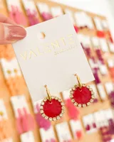 Aros colgantes con forma circular, de color rojo con borde de strass plateado y gancho dorado.