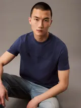 Remera azul de algodón con cuello redondo, mangas cortas y logo "Calvin Klein Jeans" estampado en el pecho.