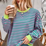 Buzo oversize de algodón frisado con diseño de rayas horizontales en tonos fucsia y celeste, cuello redondo y puños en tono tostado.